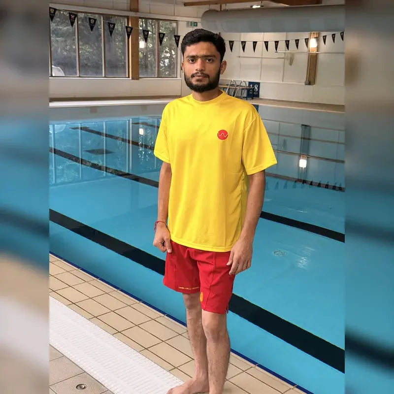 Yellow pool lifeguard t-shirt front view, worn poolside with red lifeguard shorts