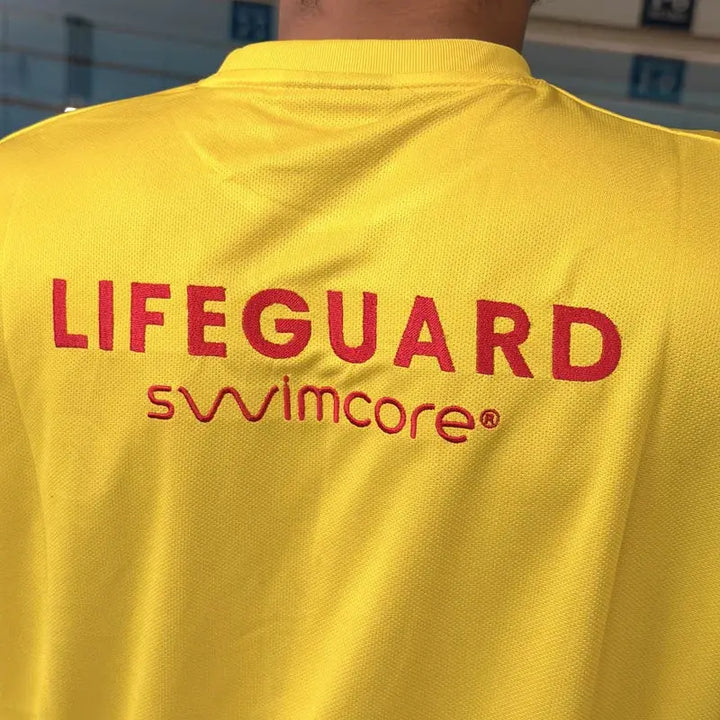 Embroidered LIFEGUARD and Swimcore lettering on the back of the yellow lifeguard t-shirt